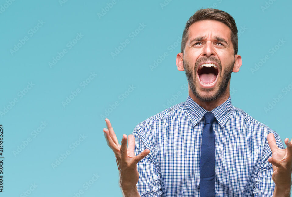 Young handsome business man over isolated background crazy and mad shouting and yelling with aggressive expression and arms raised. Frustration concept.